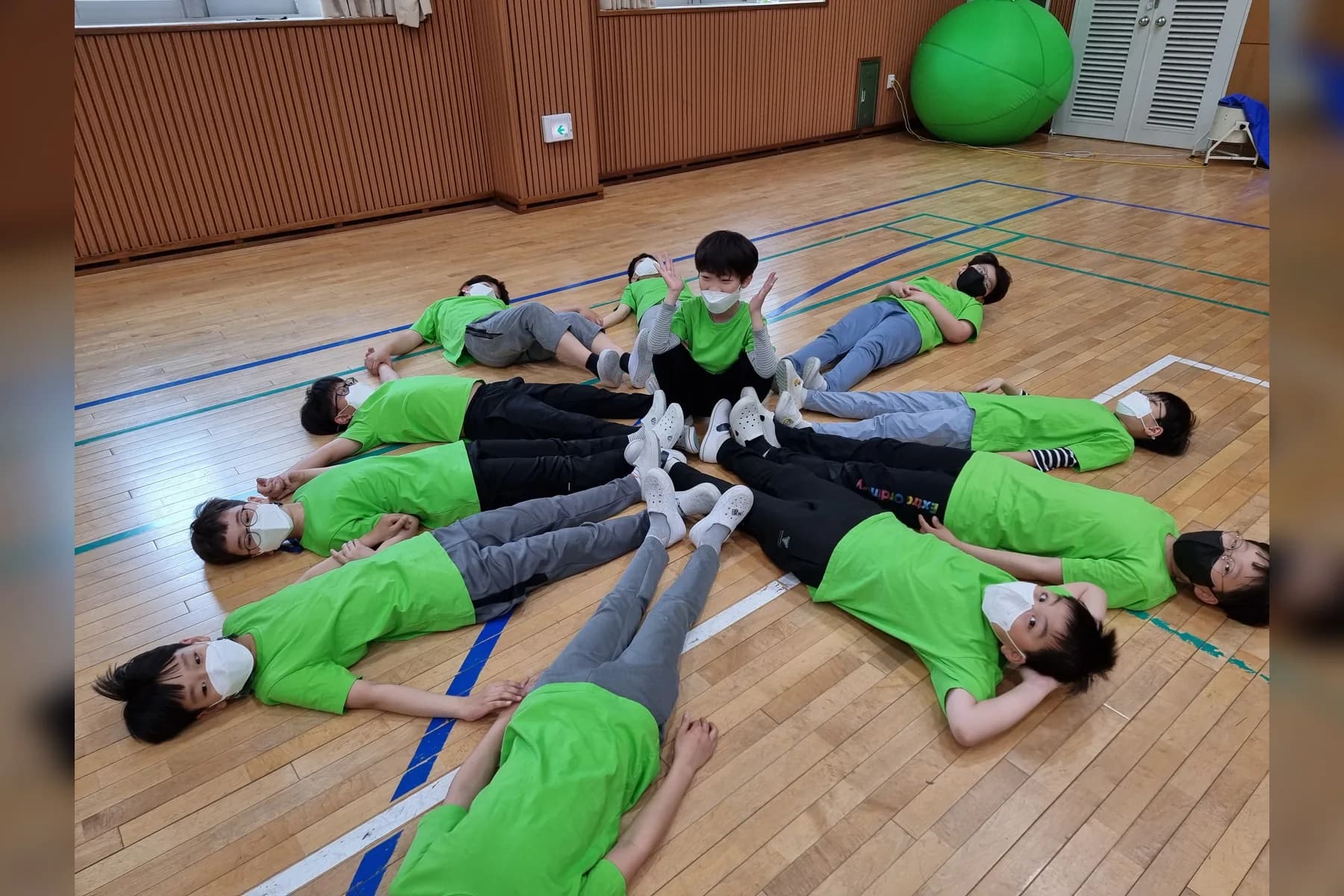 초록색 단체복을 입은 학생들이 몸으로 팀 모양을 만드는 실제 협동 운동회